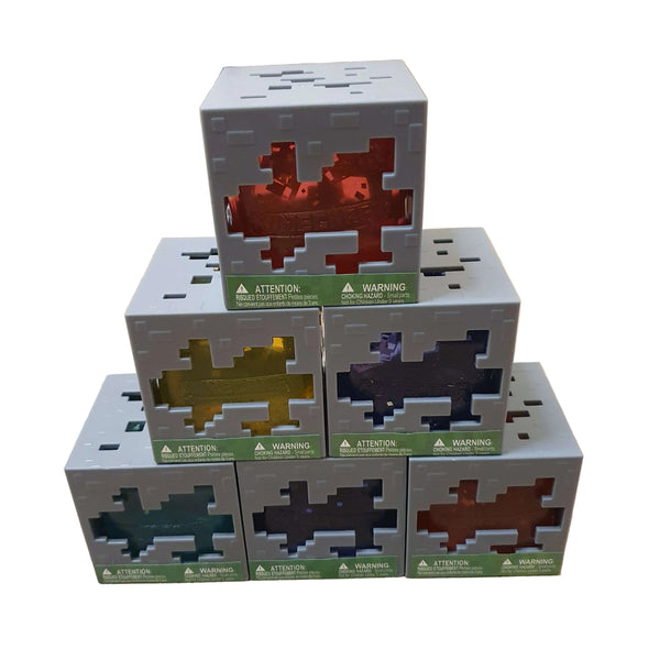 A stack of six Minecraft-themed cube-shaped boxes arranged in a pyramid on a white background. The top box is open, revealing a red pixelated interior, while the boxes below are closed with green warning labels and cutouts showing different colored pixelated interiors in gray, gold, purple, teal, black, and brown.